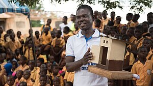Mann erklärt ghanaischen Schulkindern mit einem Modell den Bau einer Latrine im Rahmen eines Hygieneprojekts