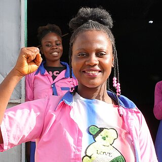 Mädchen in bunten Klamotten reckt selbstbewusst ihre Faust in die Luft