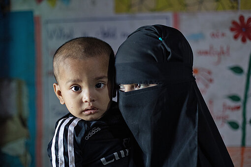 Frau im Niqab mit Kleinkind auf dem Arm