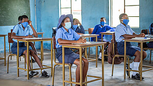 Schülerinnen und Schüler mit Masken im Klassenzimmer während des Unterrichts in Afrika