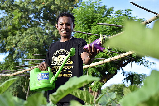 Junge wässert Gemüsegarten in Indonesien 