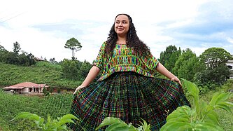 Jaqueline steht in der Mitte einer grünen Wiese und blickt selbstbewusst in die Kamera.