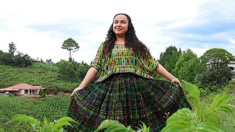Jaqueline steht in der Mitte einer grünen Wiese und blickt selbstbewusst in die Kamera.