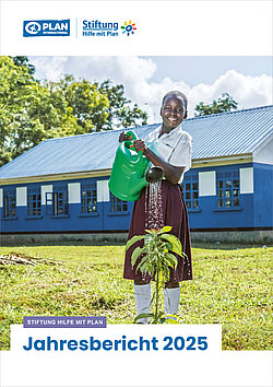 Ein lächelndes Mädchen im Schuluniform gießt im Rahmen eines Projekts von Plan International eine junge Pflanze vor einer blauen Schule – Symbol für Nachhaltigkeit und Bildung.