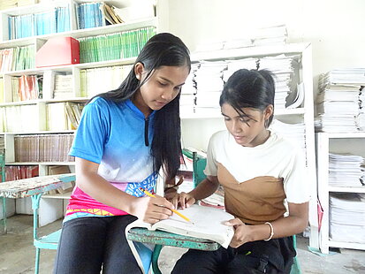 Ein Mädchen hilft einem anderen bei ihren Schulaufgaben