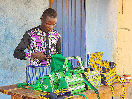 Junger Mann schneidet ein Stück Stoff zurecht