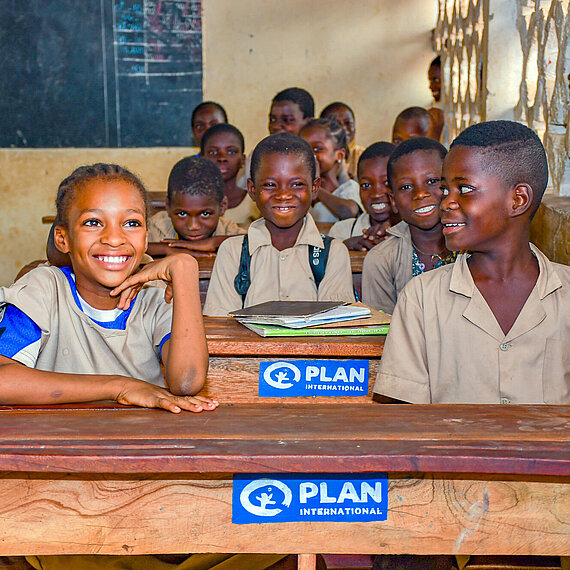 Bild von Schulkindern in Benin im Unterricht, gefördert durch Plan International Lachende Schulkinder in einem Klassenzimmer in Benin, unterstützt von Plan International