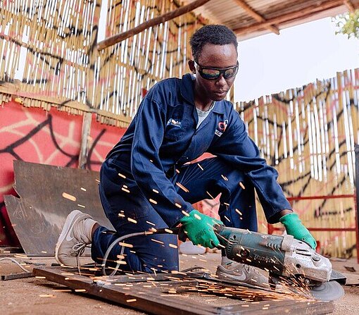 Auszubildende schleift ein Stück Metall