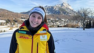 Magdalena Matschina steht in einem Schneegiebt, trägt eine gelbe Skijacke und lächelt in die Kamera.