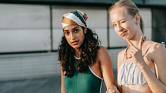 Zwei Mädchen halten Hand, eine zeigt mit der anderen Hand das Peace-Zeichen