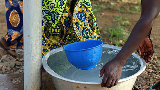 Frauen schöpfen frisches Wasser in Eimern und Schalen Frauen schöpfen frisches Wasser mit Eimern und Schalen