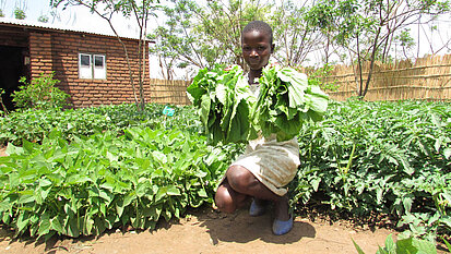 Bild: Eine Schülerin zeigt, was sie in ihrem neuen Garten angebaut hat.