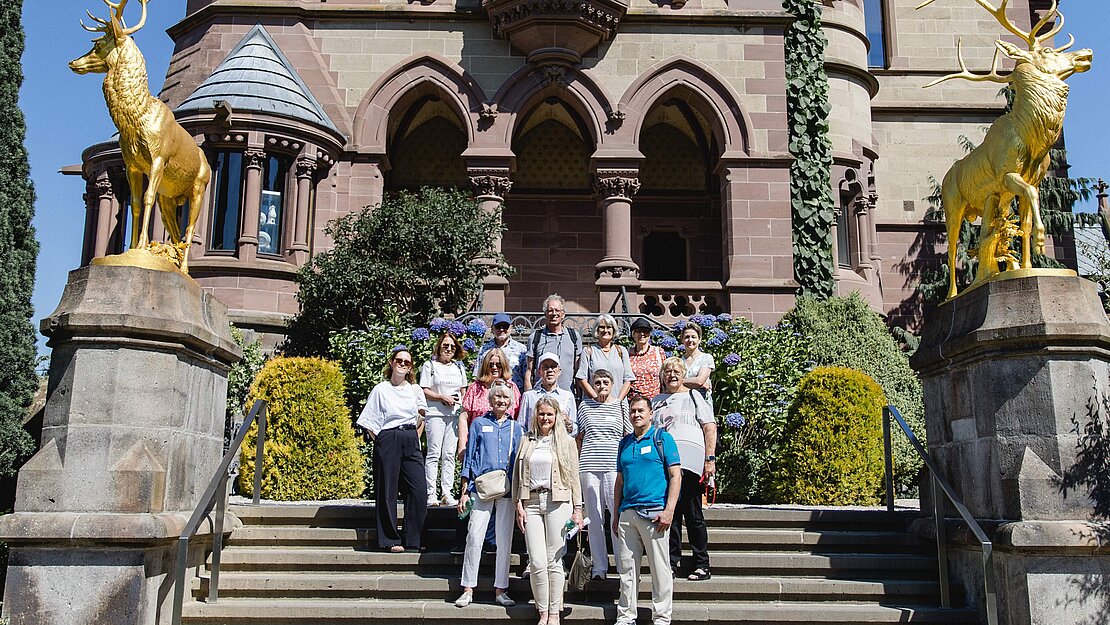 Eine Gruppe von Menschen steht vor Schloss Drachenburg.