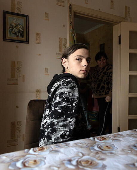 Vitali im Haus der Pflegeeltern sitzend an einem Tisch 