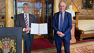 Dr. Norbert Kloppenburg (links) erhält für seine sozialen Verdienste in der Entwicklungszusammenarbeit im Beisein von Dr. Werner Bauch das Verdienstkreuz Erster Klasse des Verdienstordens der Bundesrepublik Deutschland verliehen. © Plan International