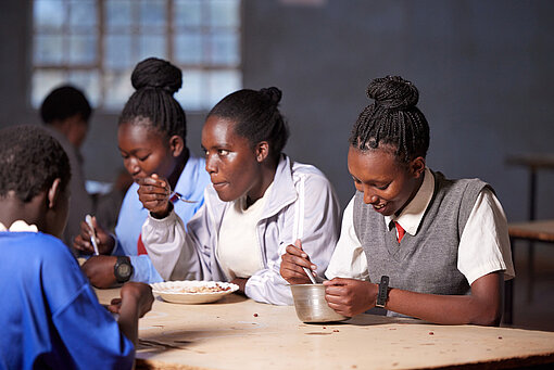 Vier junge Frauen essen an einem Tisch in der Schulkantine