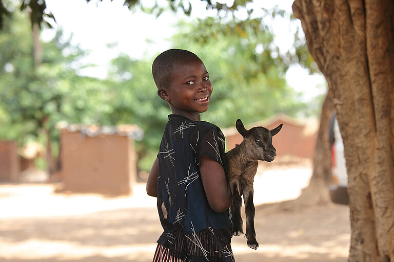 Ein Mädchen hält eine Ziege im Arm