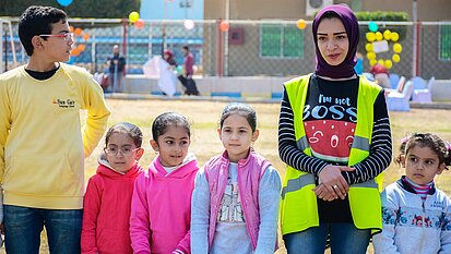 Bild: Eine Betreuungsperson steht neben vier Mädchen