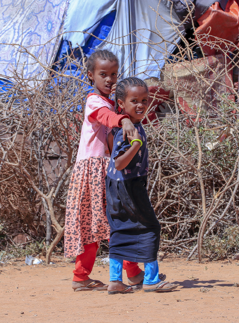 Zwei kleine Kinder laufen durch das Camp