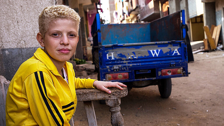 Mohamed in einer gelben Trainingsjacke auf der Straße.