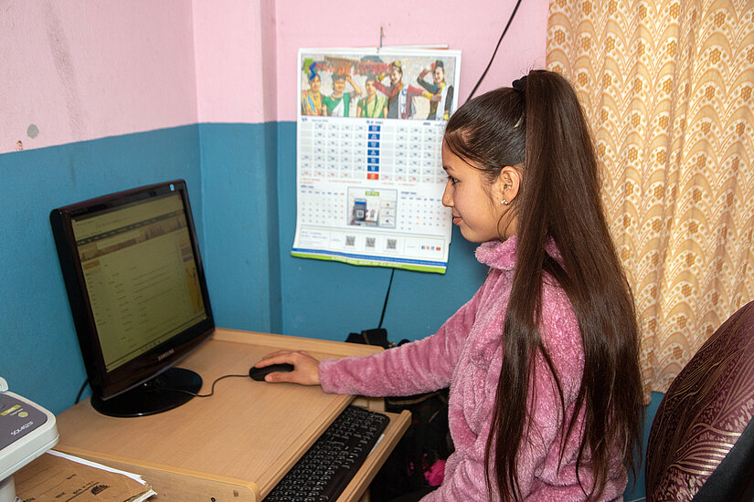 Junge Frau in Nepal arbeitet am Computer in einem Schulungsraum