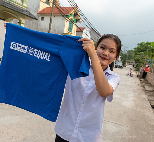 Mädchen mit "Girls Get Equal" T-Shirt Mädchen hält blaues "Girls Get Equal" T-Shirt