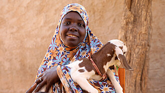 Eine Frau hält eine junge Ziege im Arm