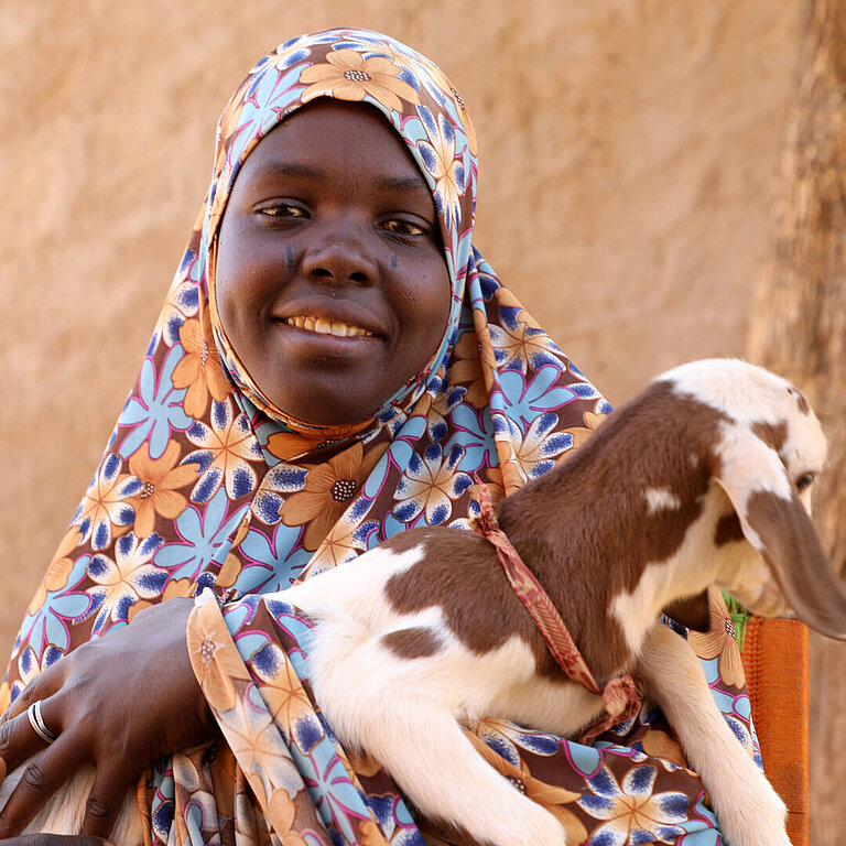 Eine Frau hält eine junge Ziege im Arm