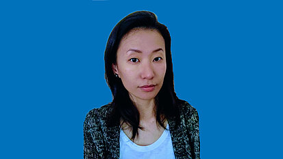Ein Portrait von Kinderschutzexpertin Yang Fu: Sie ist schlank, hat lange Haare, lächelt leicht und trägt eine leichte Jacke über einem Tshirt