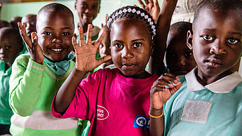 Bye Bye 2020! In unserem Jahresrückblick schauen wir auf ein herausforderndes Jahr für die ganze Welt zurück. © Plan International drei Kinder schauen in die Kamera und winken