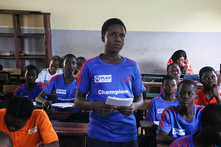 Guineische Jugendliche trägt etwas im Seminarraum vor