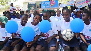 Mädchen mit Luftballons und Fußball bei einer Veranstaltung zur Förderung von Gleichberechtigung und Bildung Gruppe von Mädchen in Schuluniformen mit blauen Luftballons und einem Fußball bei einer Veranstaltung zur Förderung von Gleichberechtigung.