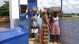 Frauen in Ghana holen Wasser an einer Wasserstelle