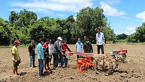 Gruppe junger Männer lernt den Einsatz landwirtschaftlicher Maschinen auf einem Feld in Laos