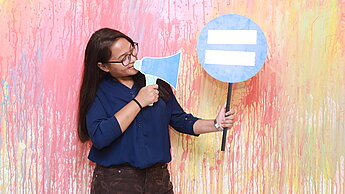 Ein Mädchen steht vor einer künstlerisch bemalten Wand.