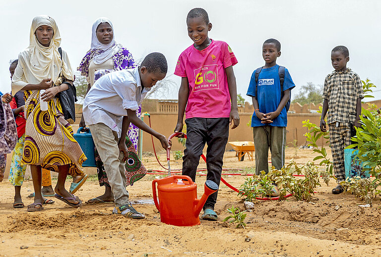 Kinder bewässern ihren Schulgarten