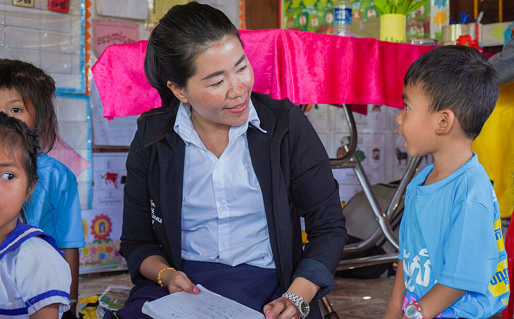 Die Lehrerin Thong Lao aus Kambodscha hilft einem Jungen dabei, das Alphabet zu lernen.