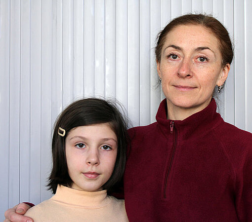 Mutter und Tochter stehen schüchtern lächelnd nebeneinander