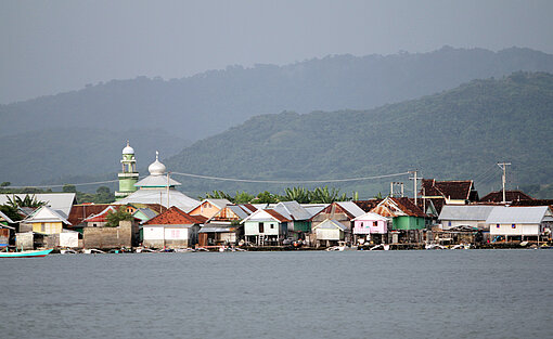 Eine Reihe Häuser auf Stelzen am Rand der Insel.