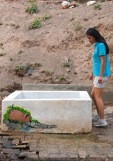 Für den Schutz des Wassers: Lizeth prüft eine der natürlichen Quellen Mädchen aus Bolivien steht am Rand eines Wasserbeckens