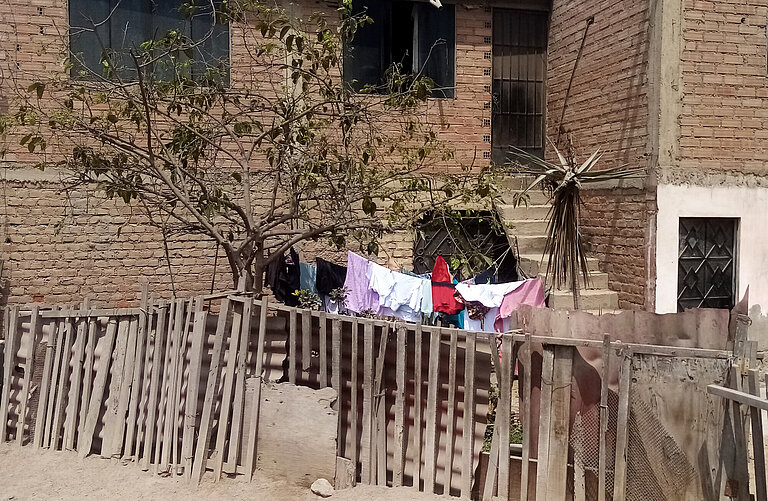 Ein Haus von außen, es ist eine Wäscheleine über den Hof gespannt und daran hängt Wäsche.