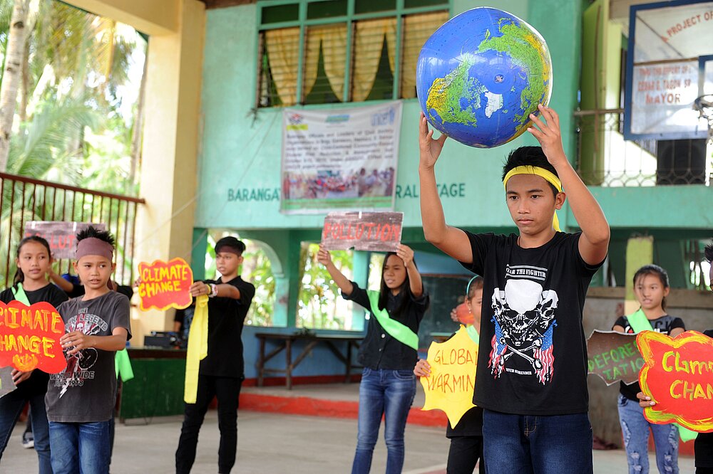 Jugendliche auf den Philippinen zeigen bei einer Klima-Aufführung selbstgestaltete Schilder zu Umweltschutz und globaler Erwärmung