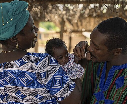 Agbeko mit seiner Frau Patience und ihrer neugeborenen Enkelin Agbekos Frau Patience hält ihre neugeborenen Enkelin im Arm. Agbeko küsst die Hand des Babys.