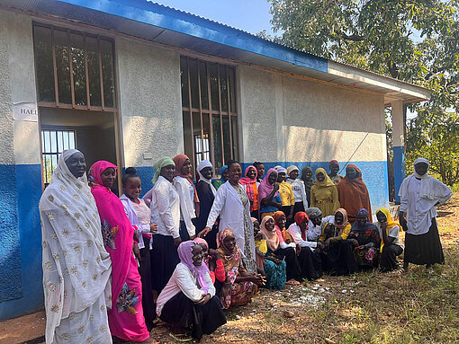 Junge Frauen und Mädchen in bunter Kleidung vor dem Gebäude des Mädchenclubs in Äthiopien, die über ihre Rechte diskutieren.