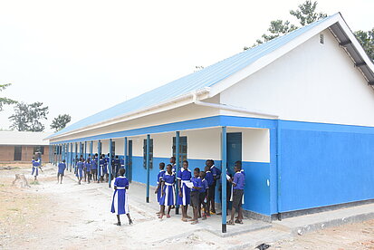 Jugendliche stehen vor einem neuen Schulgebäude