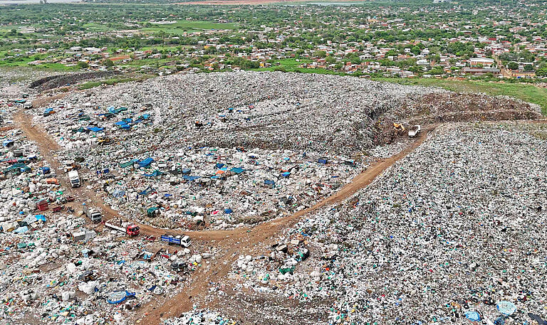 Eine Luftaufnahme zeigt Lastwagen, die vor einen großen Berg von Müll fahren
