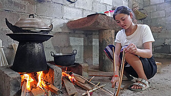 Ein Mädchen kocht an offenem Feuer