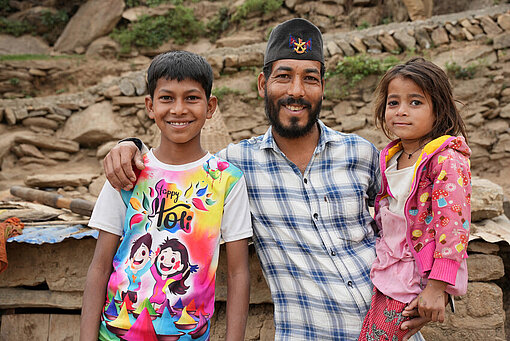 Ein Vater mit seinen zwei jüngsten Kindern vor ihrem Haus in Kalikot, Nepal.