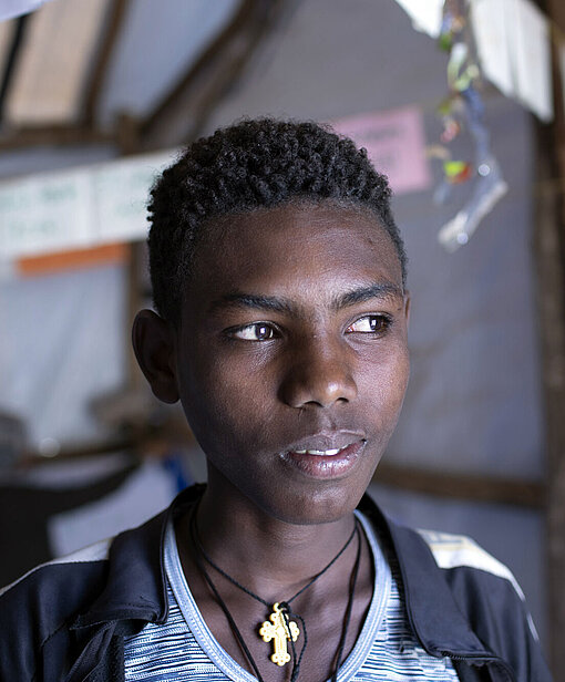 Ein Jugendlicher schaut an der Kamera vorbei in die Ferne.