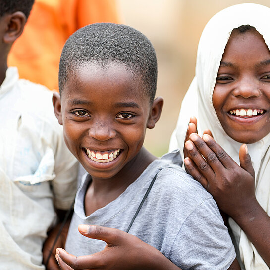 Zwei Kinder aus Tansania lachen in die Kamera.